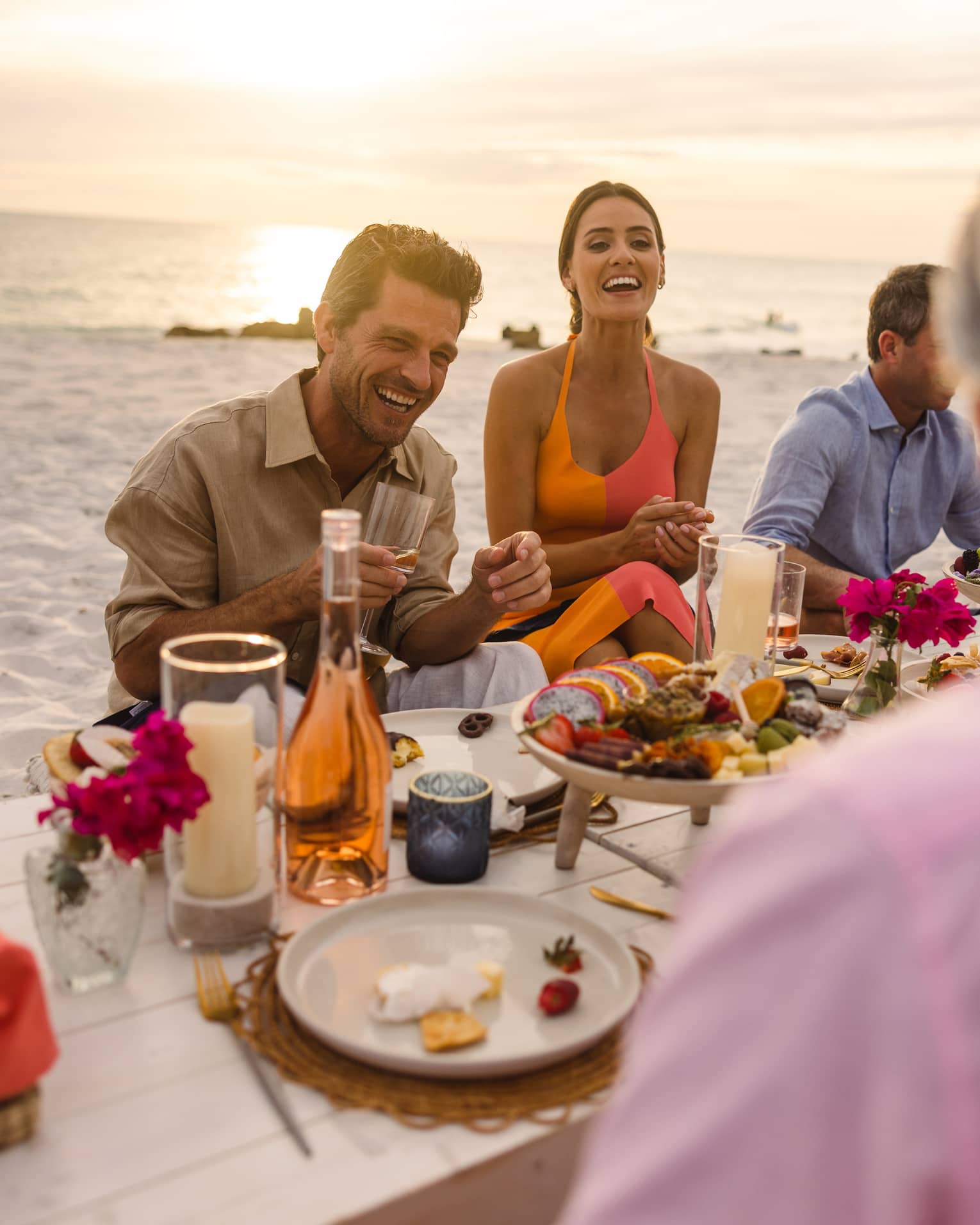 Guests sitting at a picnic table on the beach near the ocean