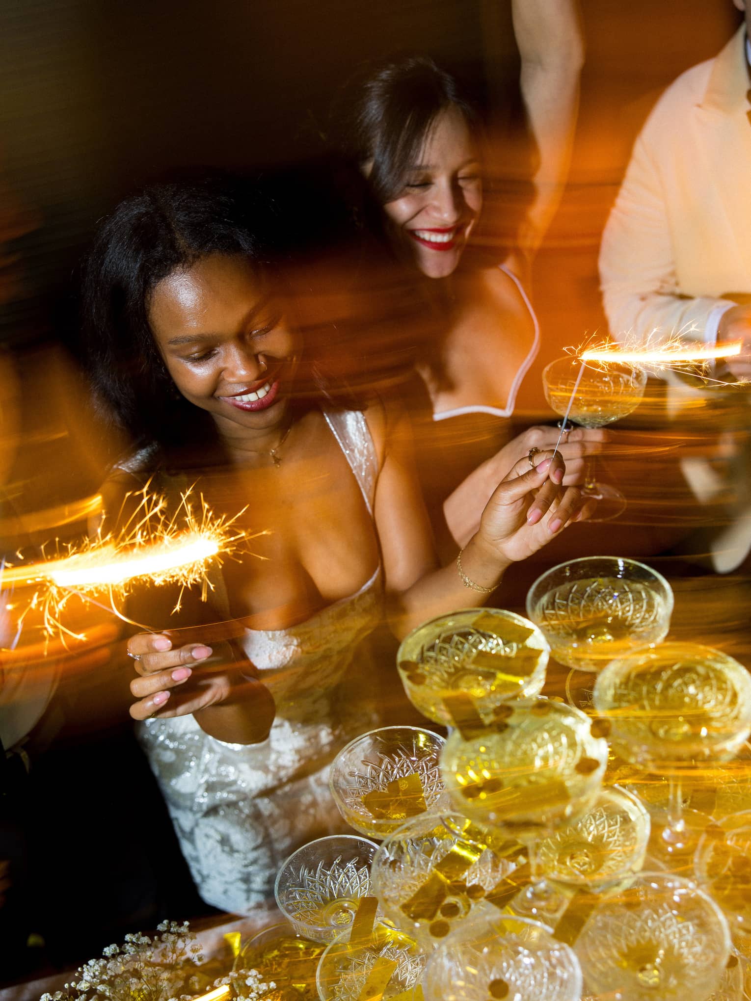 Two women dance in front of champagne tower