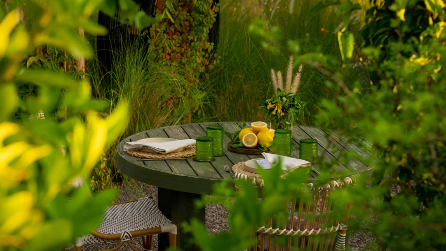 A round wooden table for two tucked in an intimate garden setting