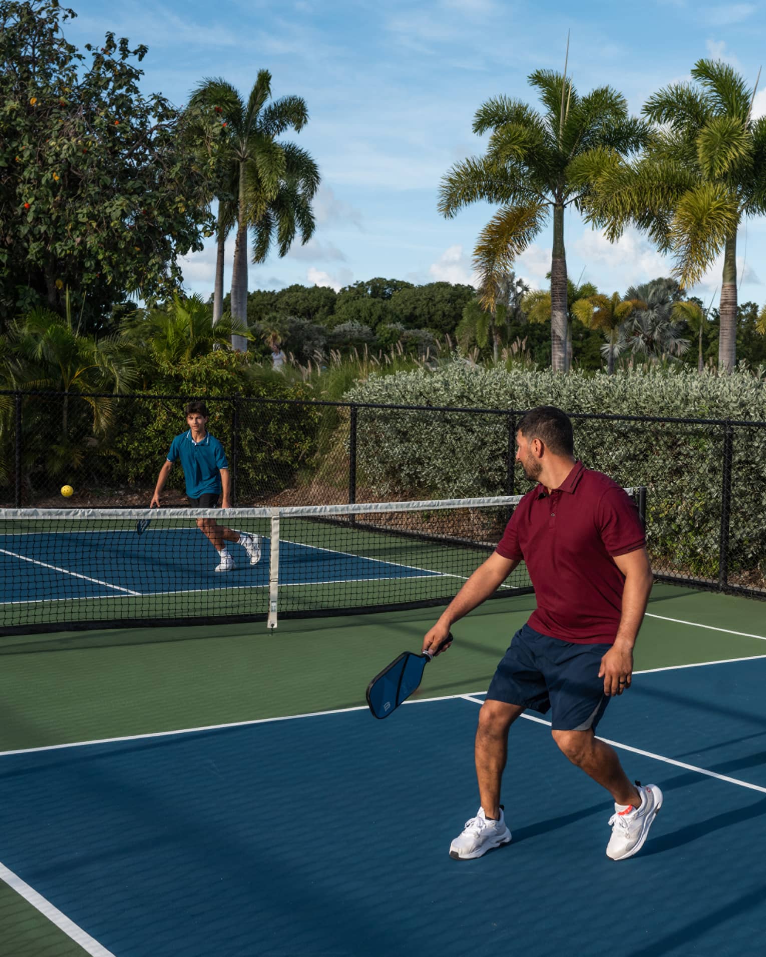 Guests playing pickleball on a pickleball court surrounded by palm trees