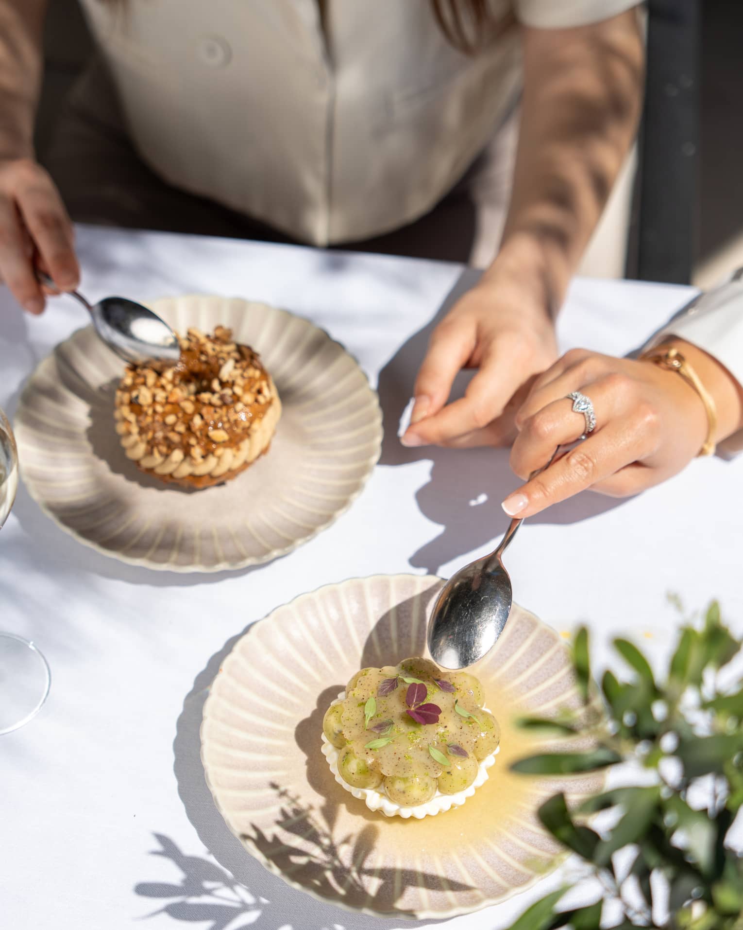 Two people partake of elegant desserts on artistic scallop-edged plates.