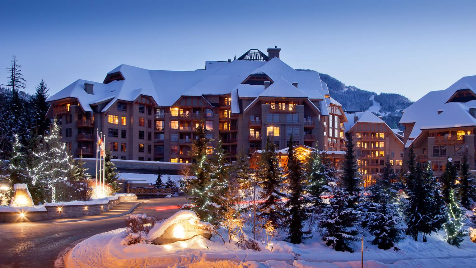 snowy four seasons hotel whistler ski lodge at dusk with illuminated windows snow covered