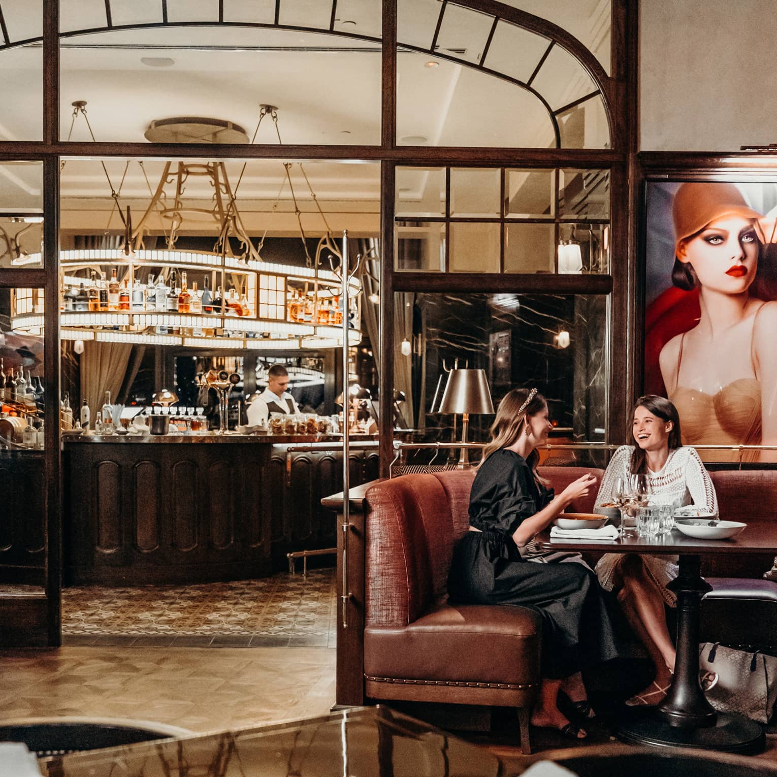 Two women sit on leather booth in restaurant