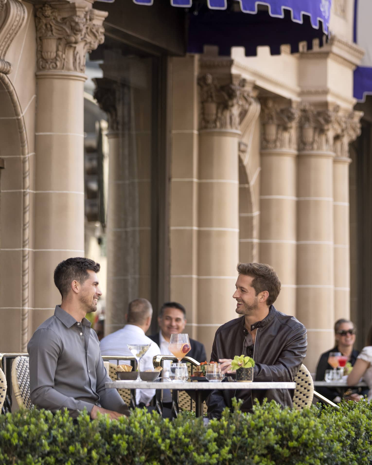 Two men eating at a patio outside.