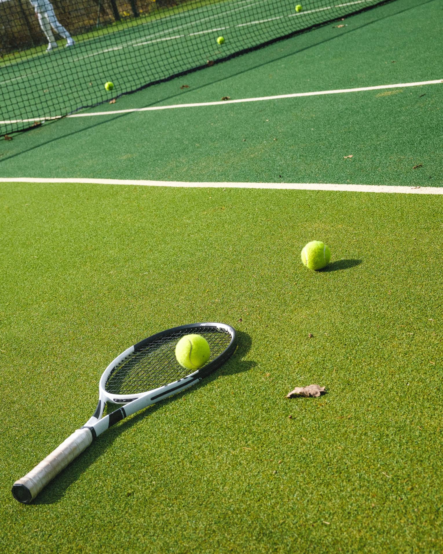Tennis racquet and two tennis balls on two-tone tennis court