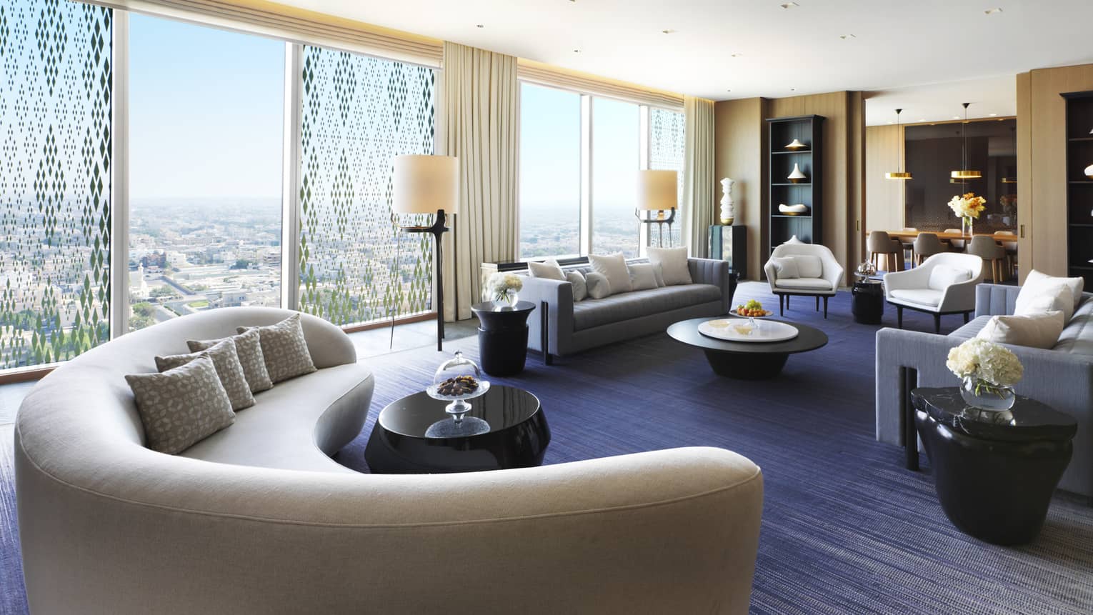 State Suite modern curved sofa in front of wall of windows, seating area