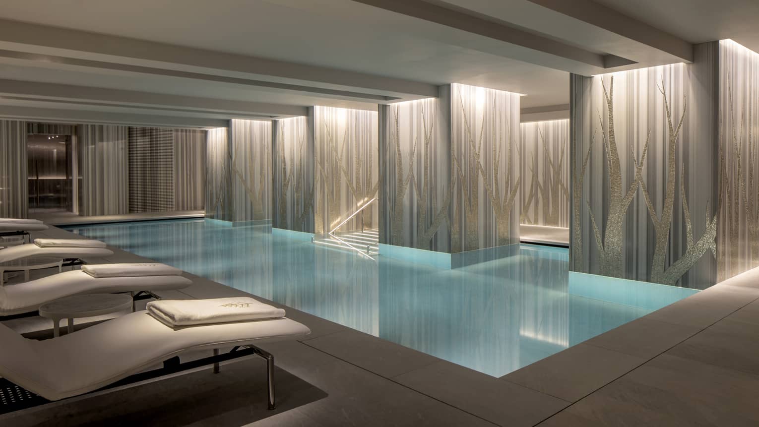 View of indoor serenity pool with illuminated classic columns and blue water