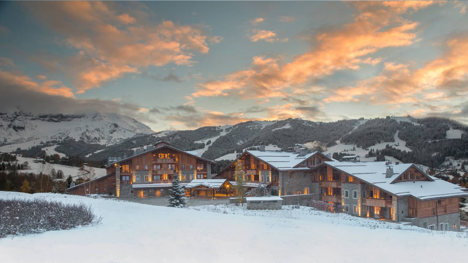 Four Seasons Hotel Megeve ski resort with lights at sunset on snowy mountain