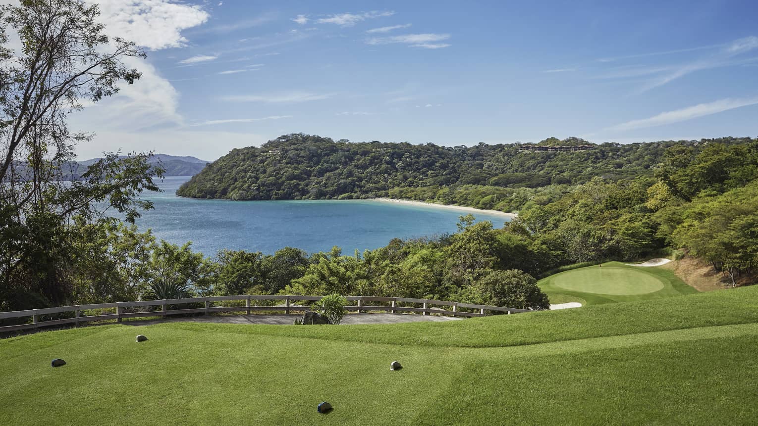 Green golf course driving range lawn and path on hills overlooking ocean