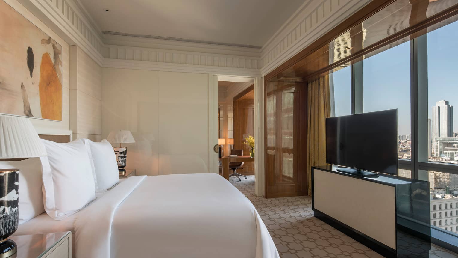 Deluxe Suite bed in front of dresser, TV, large window