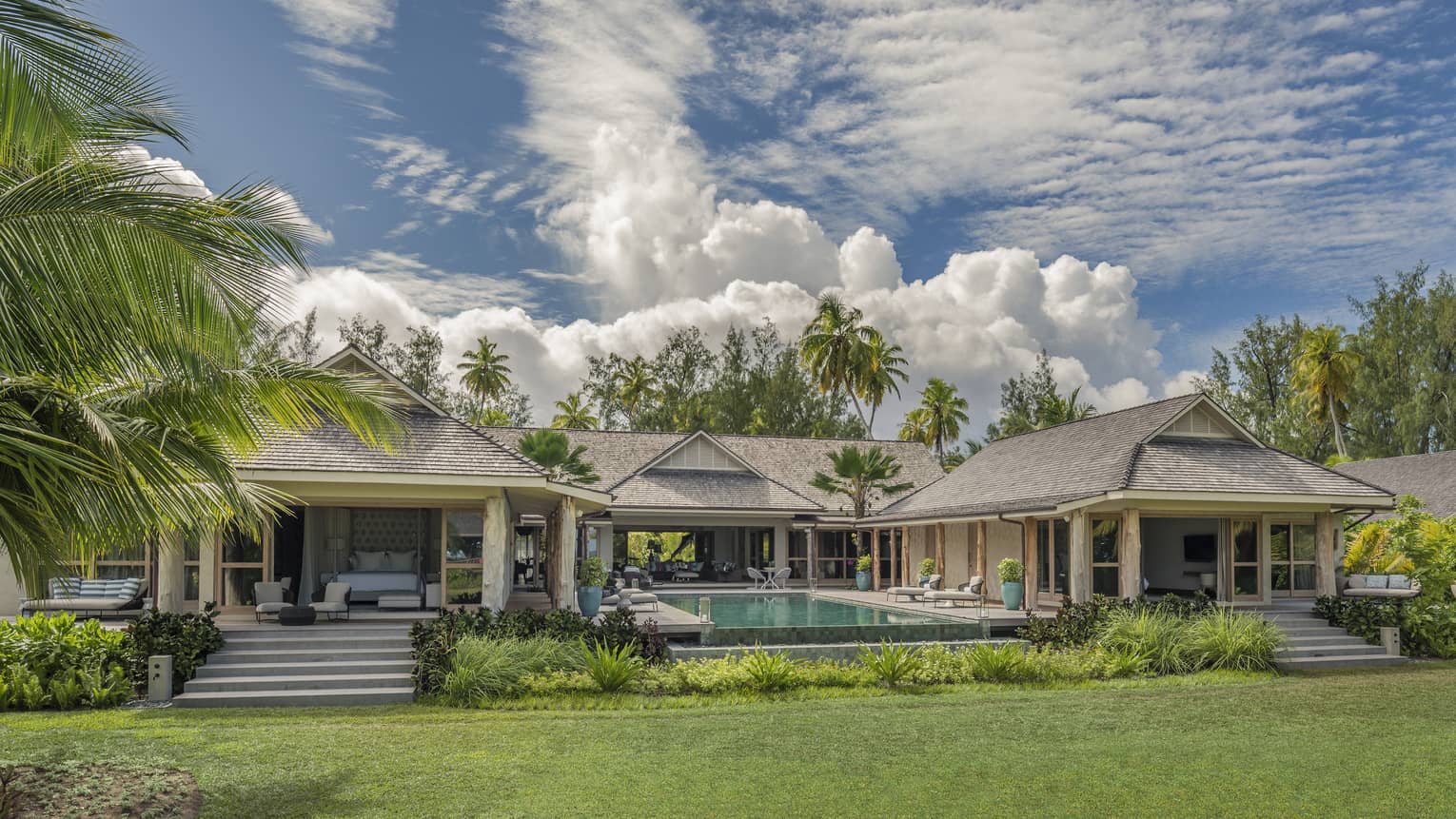 Residence villa with three buildings surrounding private pool, surrounded by palm trees