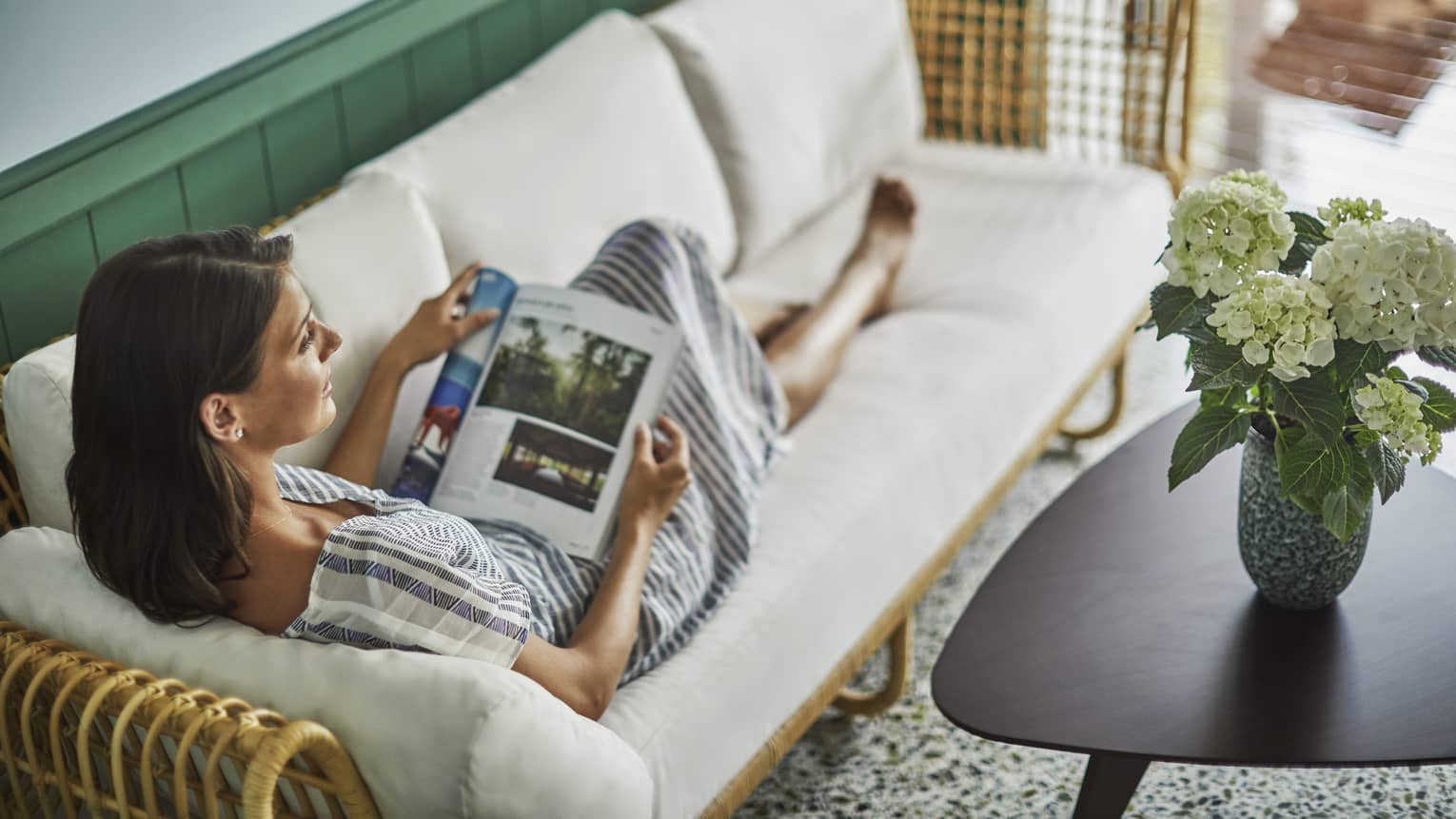 Private spa cabanas offer privacy. Woman stretches out on a sofa, reads magazine
