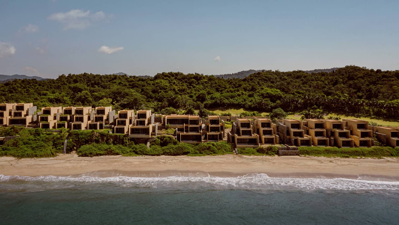 Resort rooms located along the beach, with natural reserve in the background