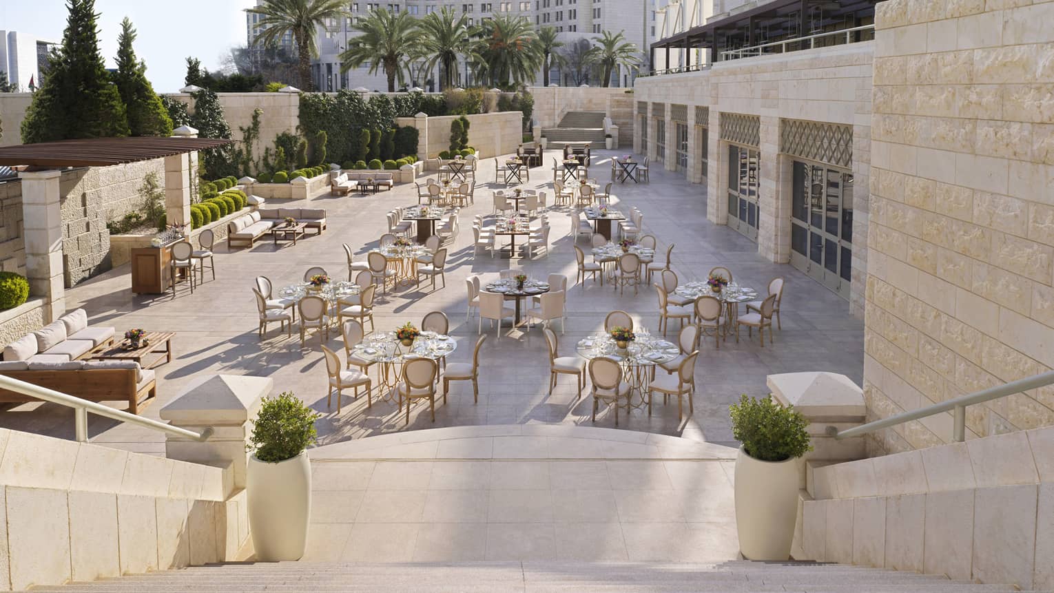 A descending staircase leading towards a series of golden chairs and tables.