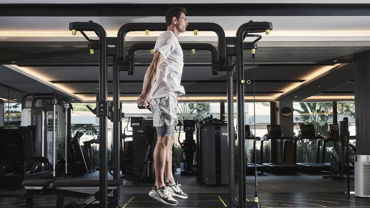 Man in athletic wear jumping vertically beside workout equipment in gym