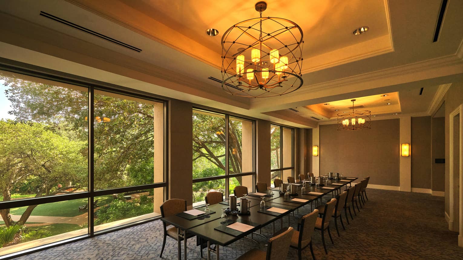 A meeting room with floor-to-ceiling windows and two chandeliers