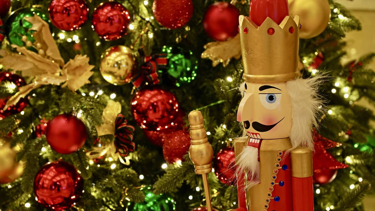 Nutcracker stands in front of a Christmas tree