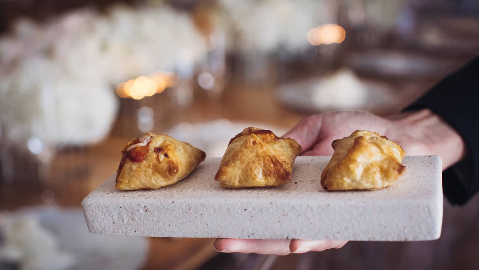 Close up of three puffed pastries on stone tray