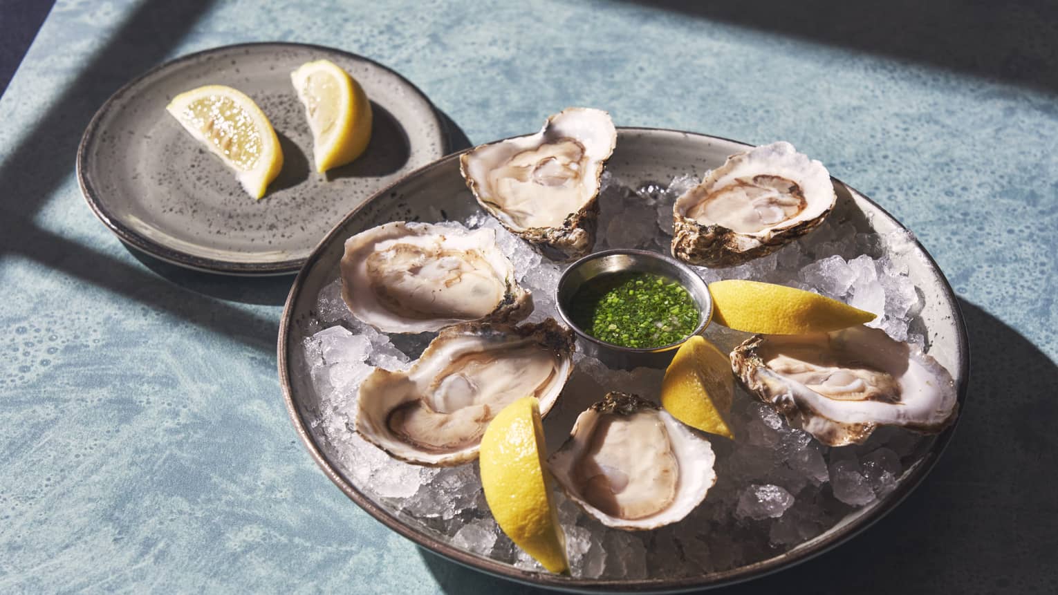 Five oysters with lemon slices and mignonette sauce.