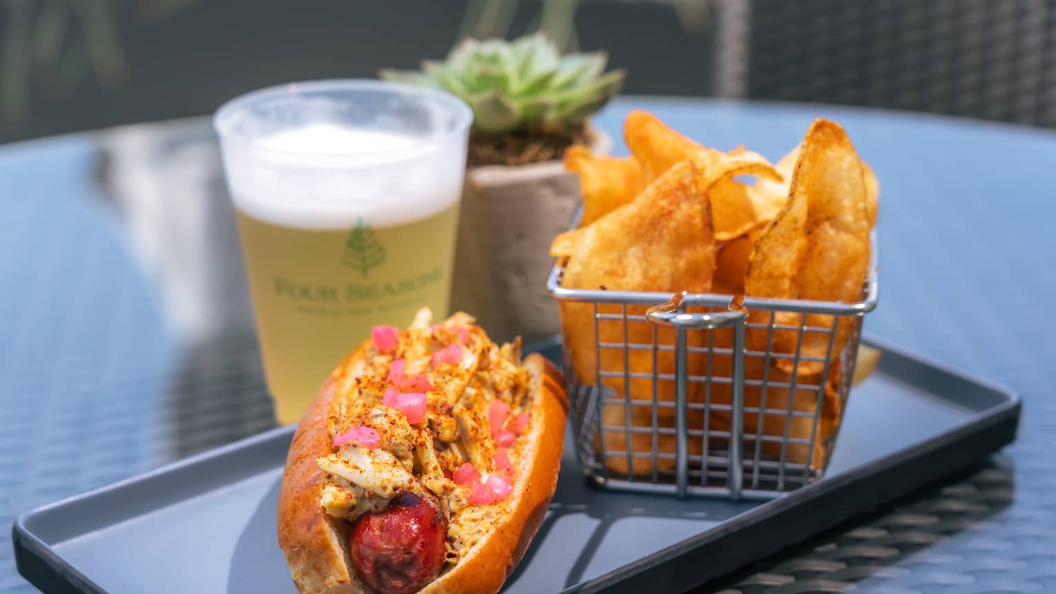 Hot dog with toppings and chips on the side.