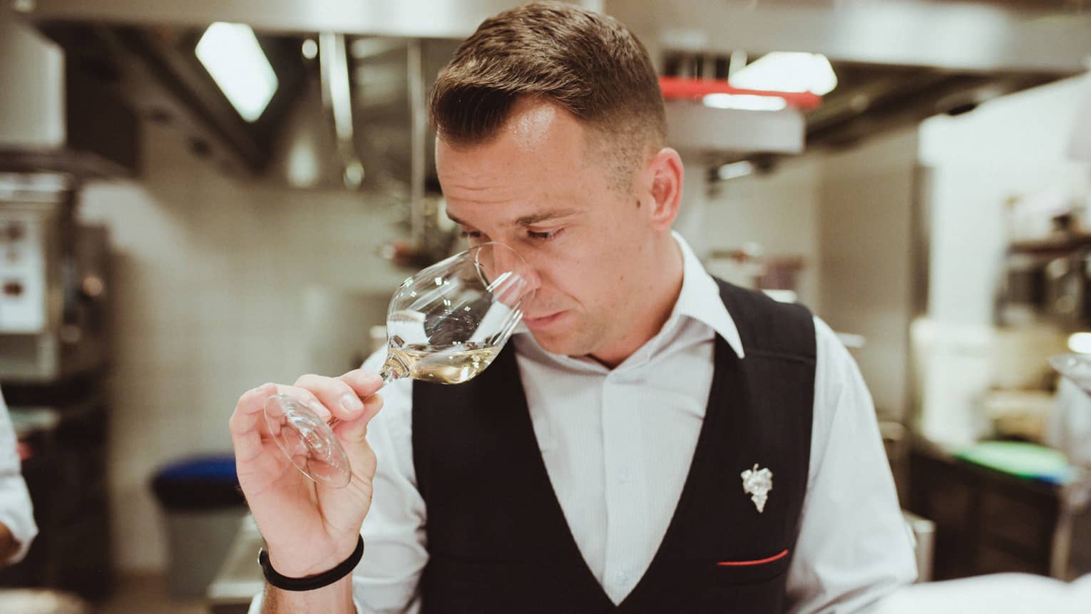 Sommelier holds a wine glass and sniffs white wine 