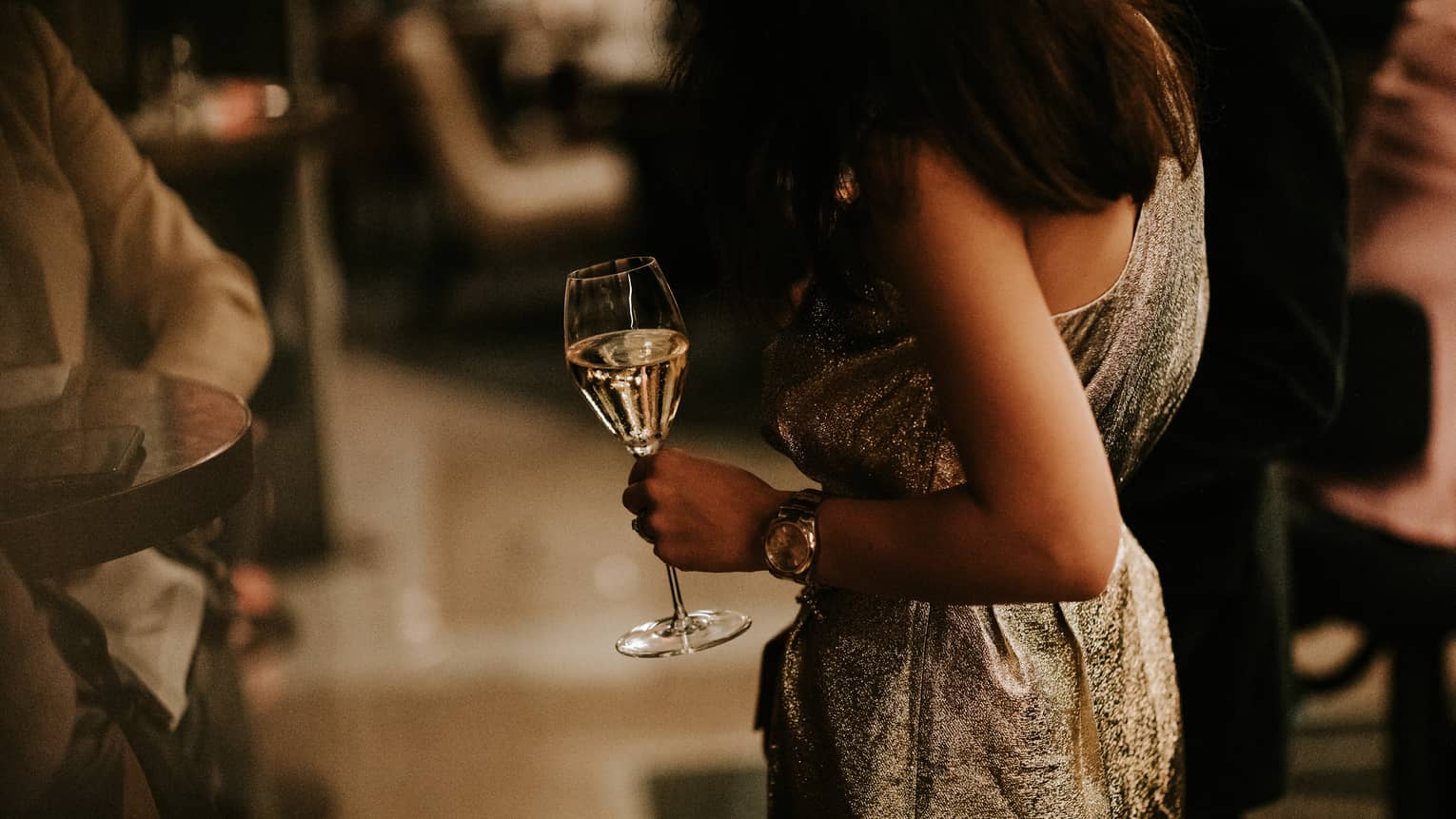 Woman in gold dress holding a glass of white wine