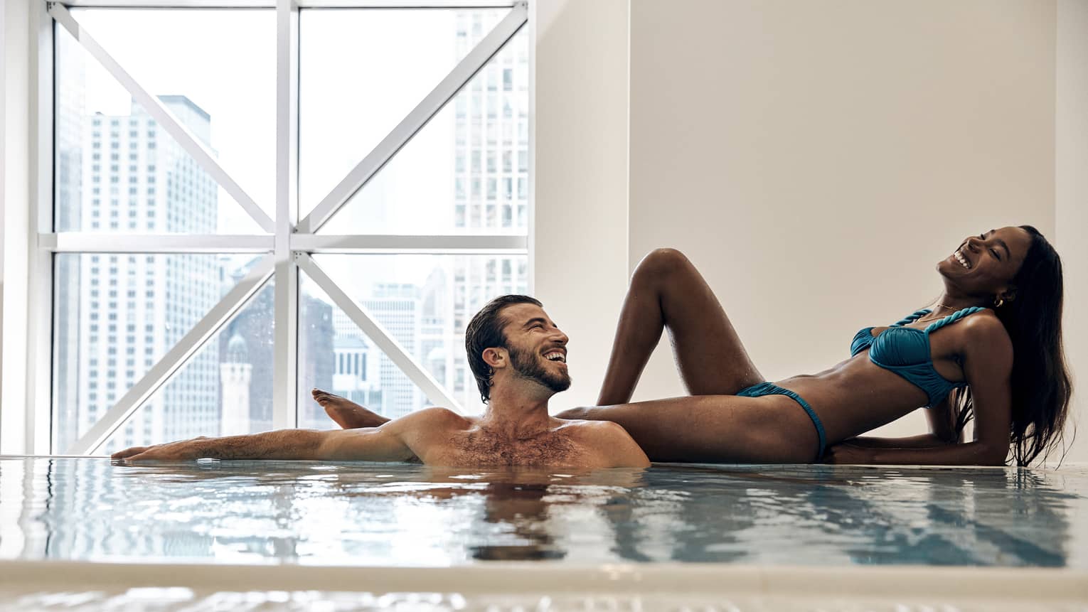 A man and woman lounging by a pool.