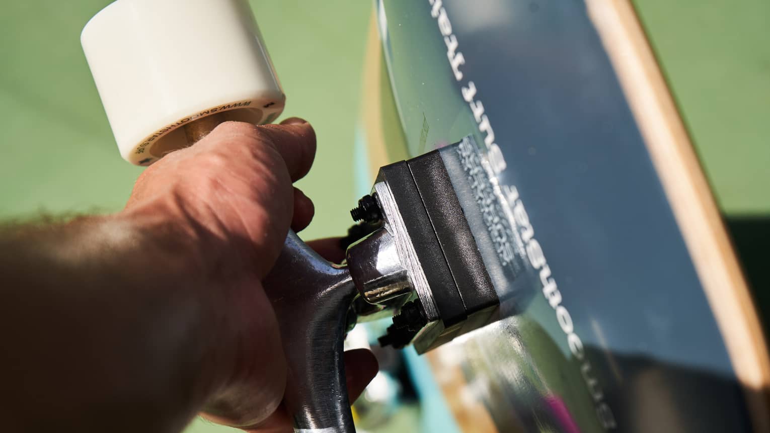 Close up of hand holding onto wheel bar of a skateboard