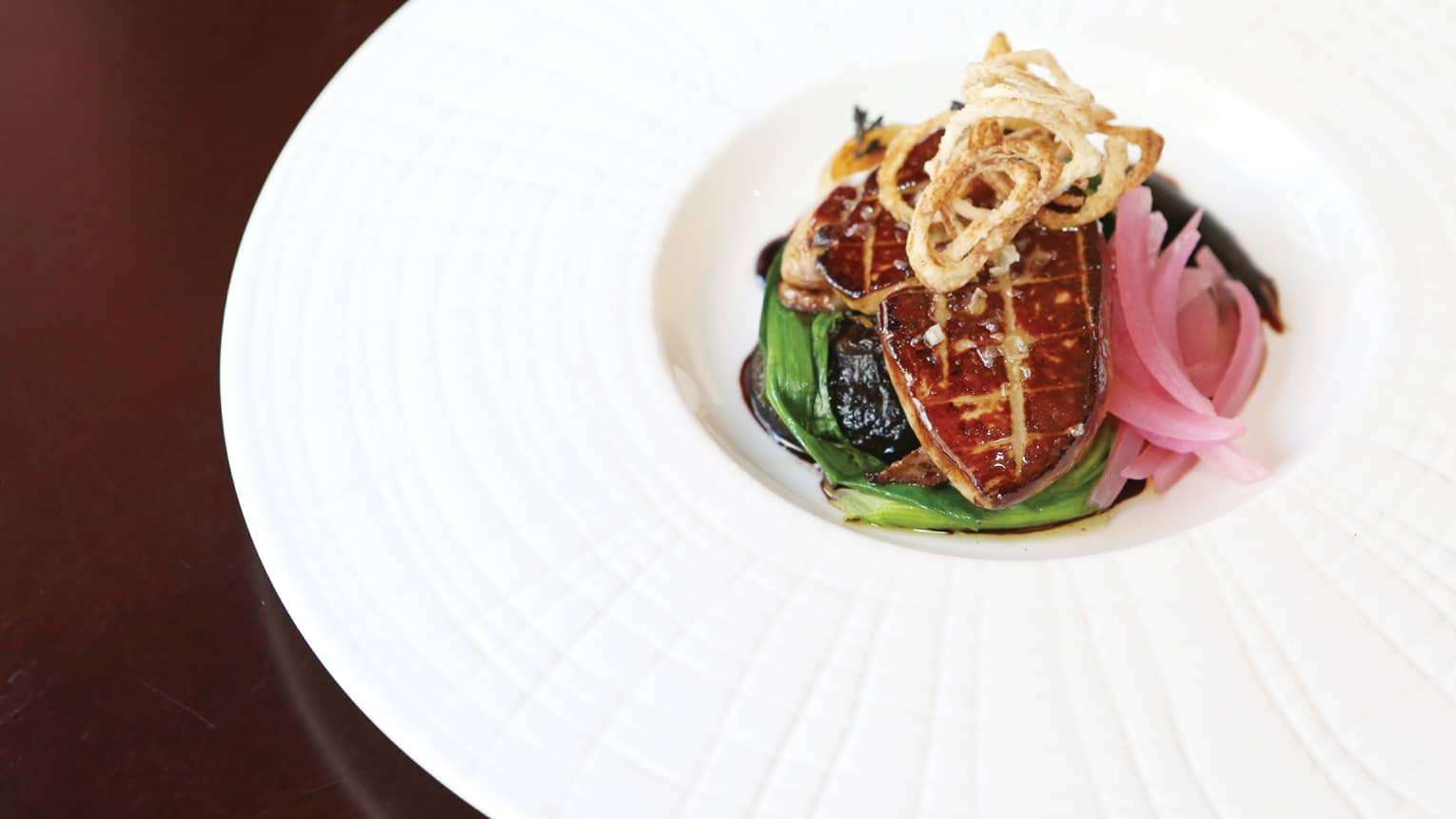 Gourmet Foie Gras topped with crispy onions in large white dish