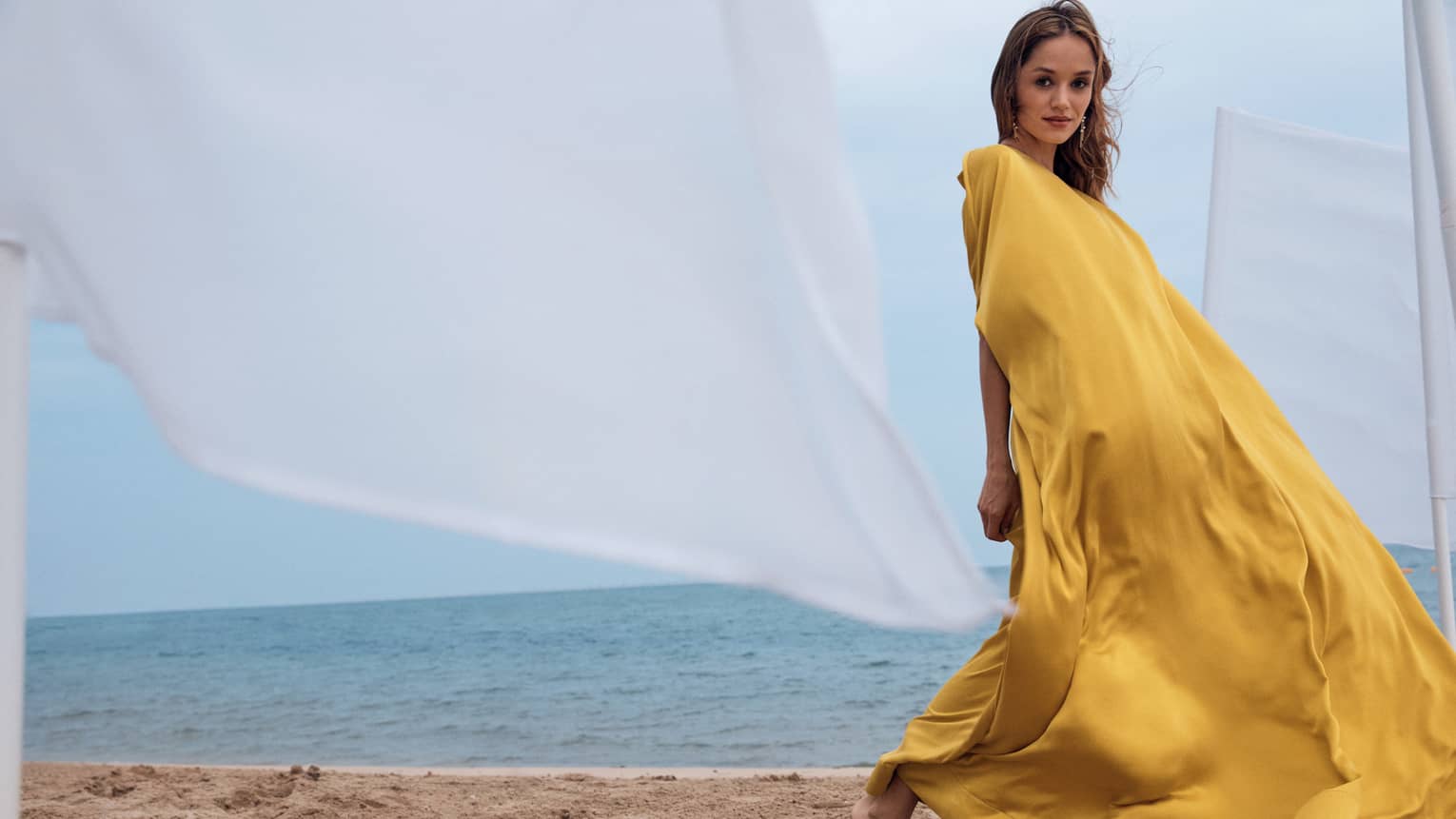 Woman in yellow silk dress on the beach