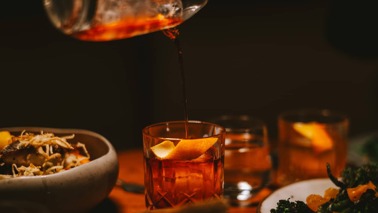 Pouring a drink into a glass with an orange slice.