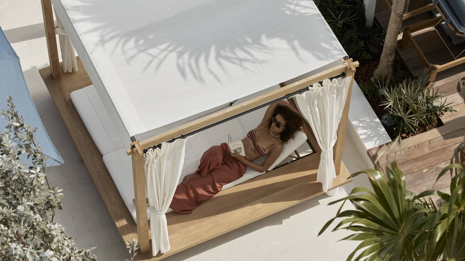 Aerial view of woman lounging in a covered poolside daybed