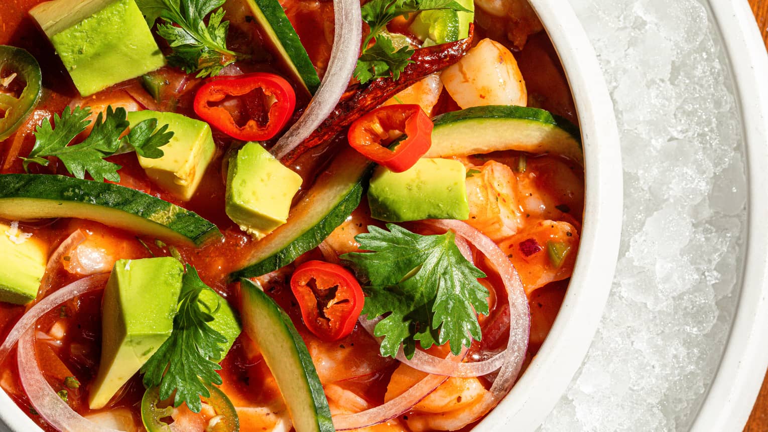 A bowl of colourful food items sits within a larger bowl of crushed ice.