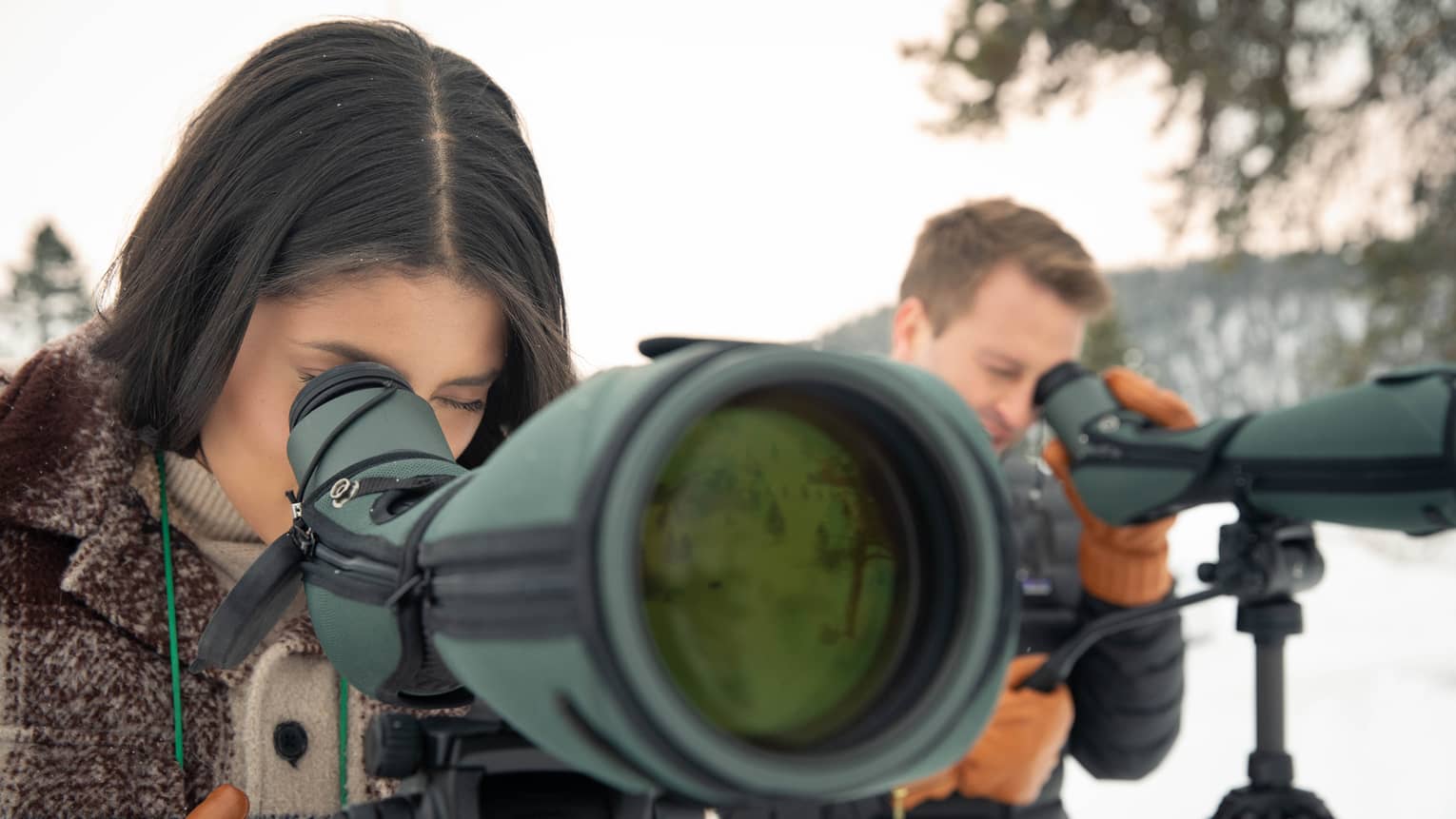 Two people standing in the snow and taking pictures with cameras