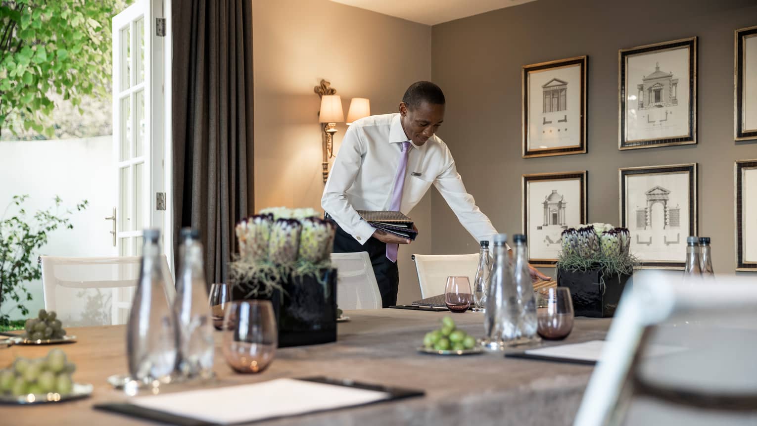 Man in dress shirt and tie sets menu on conference table