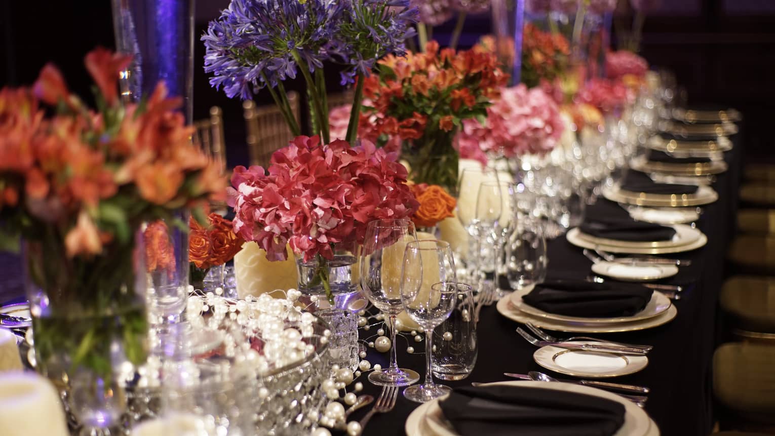 Wedding reception table setting, pink flowers in crystal vases, black napkins on plates