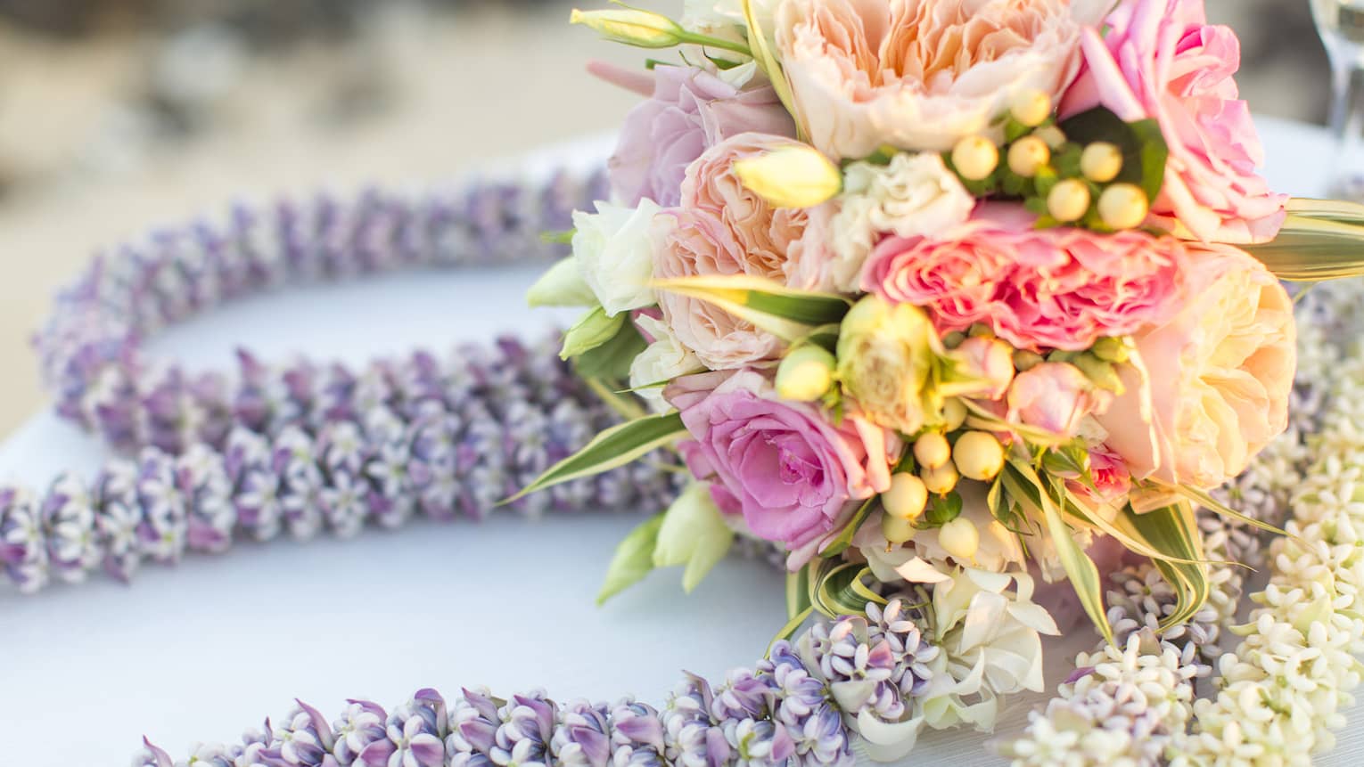 Pink and white floral wedding bouquet on purple flower garlands