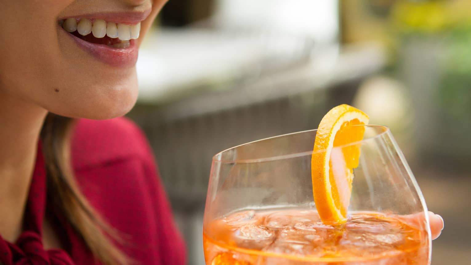 Woman holding a wine glass with an orange slice.