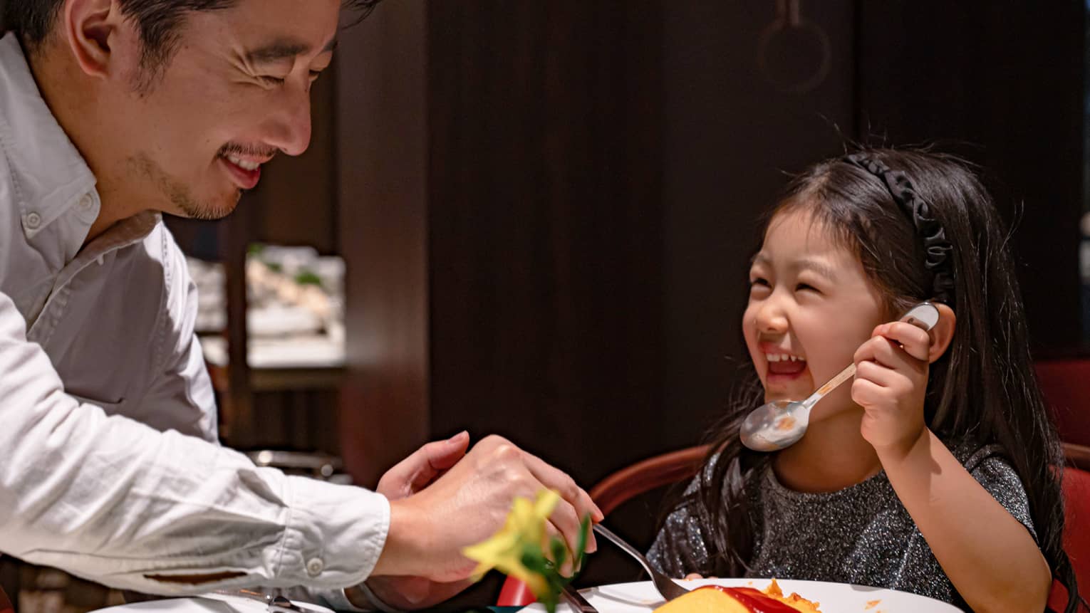 Smiling young girl and her dad dig into omurice topped with ketchup