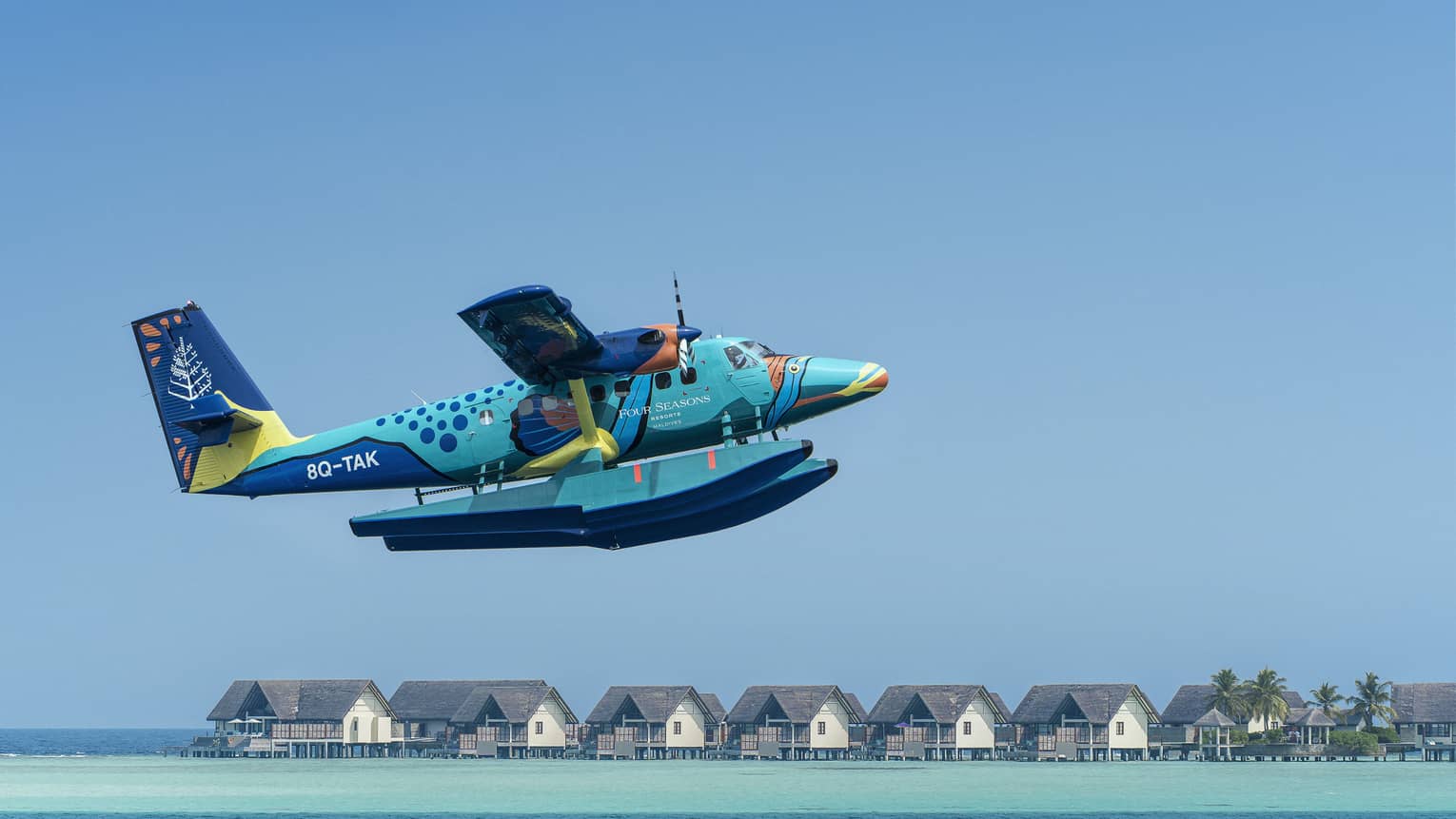 Maldives Sea Plane taking off with water villas and palm trees in the background