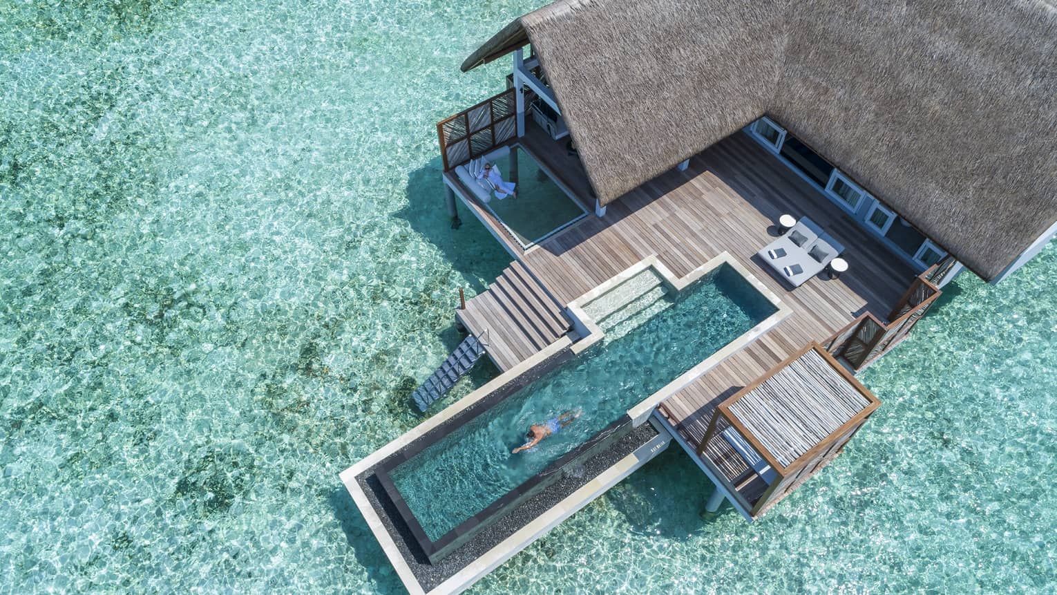 Aerial view of water villa with long swimming pool over lagoon