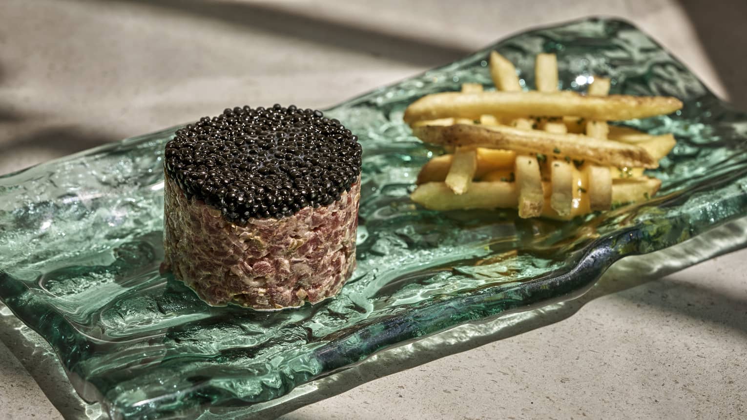 Turquoise glass plate with french fries and molded caviar
