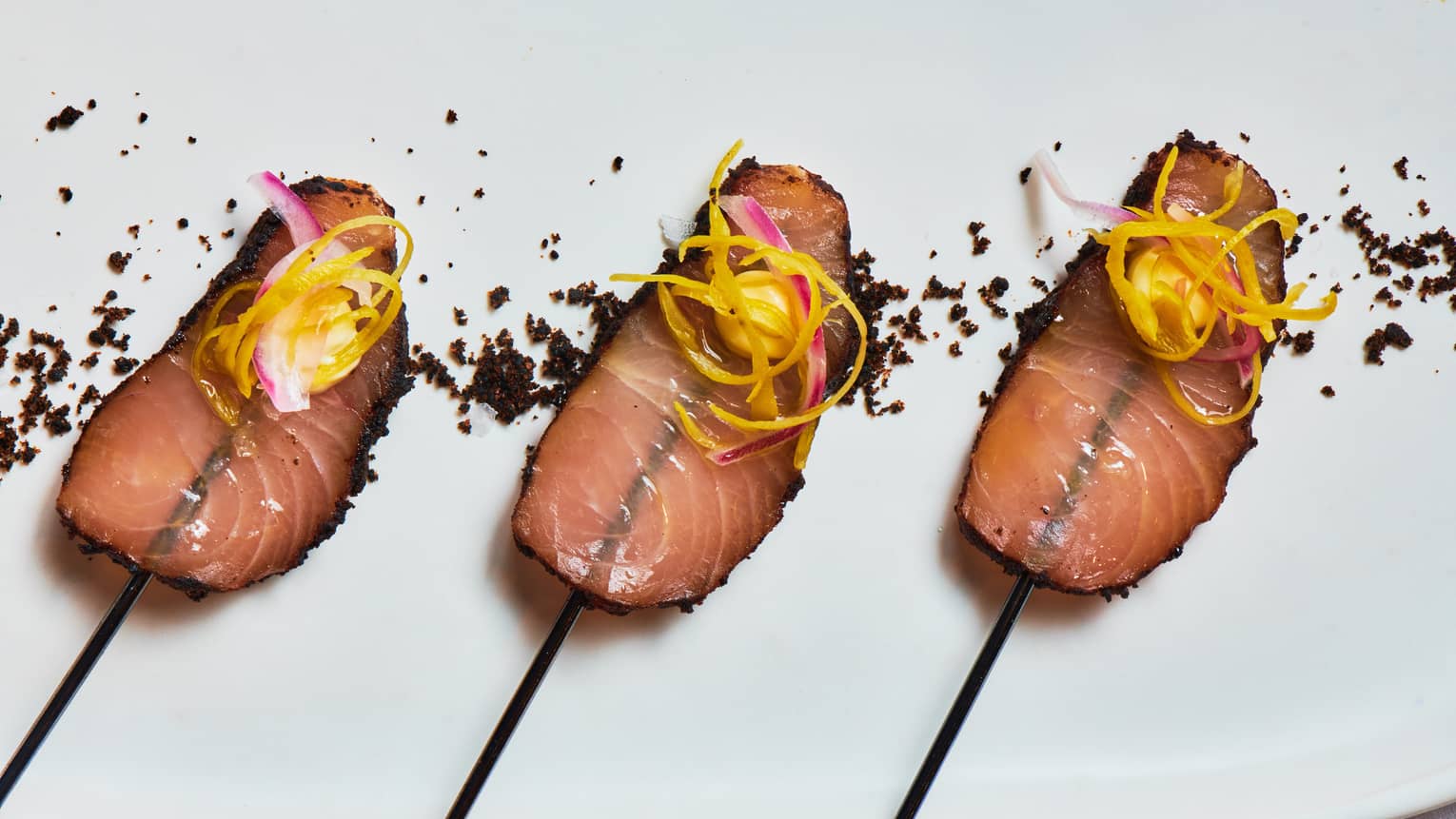 Thinly sliced charred meat served on skewers and garnished with peeled vegetables