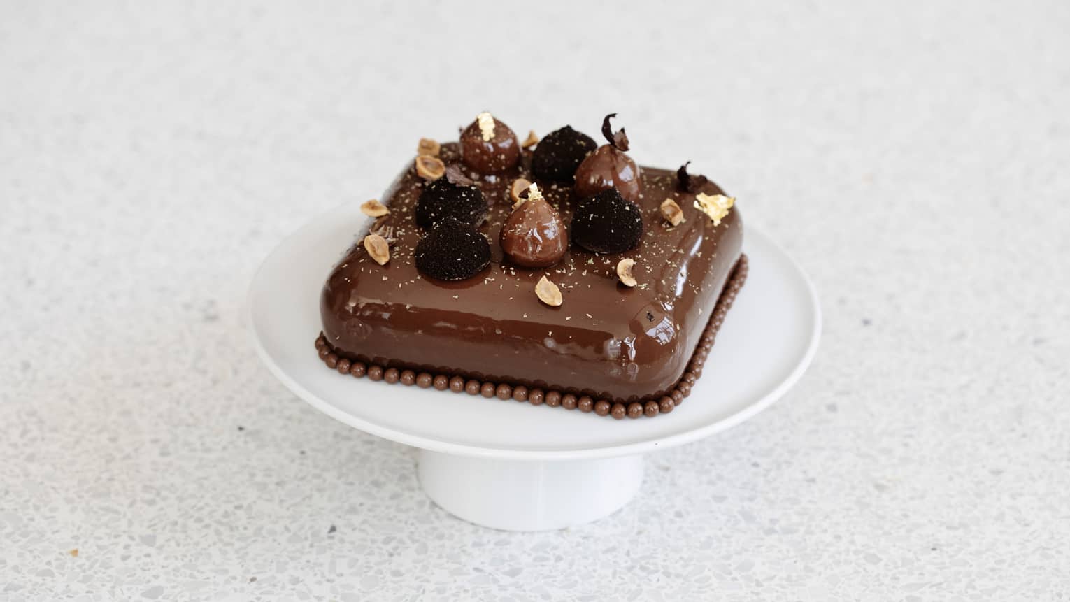 A square chocolate cake on a white tray.