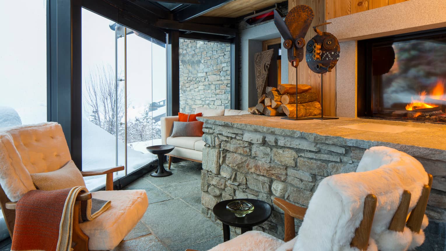 Cigar Room plush white lounge chairs by stone ledge with logs, sculptures, gas fireplace