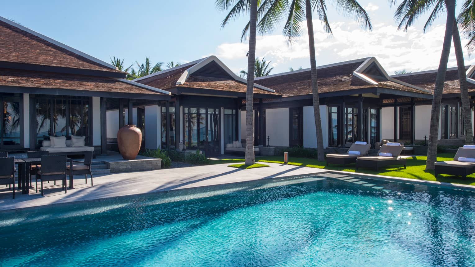 Five bedroom pool villa exterior. tall palm trees around outdoor swimming pool