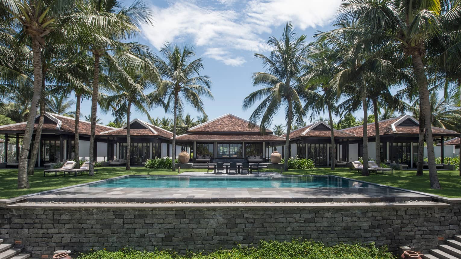 Ocean-View Villas behind large stone outdoor swimming pool, tall palm trees
