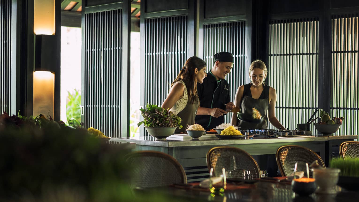 Chef, two women look at pan on kitchen range at Hoi An Cooking Academy