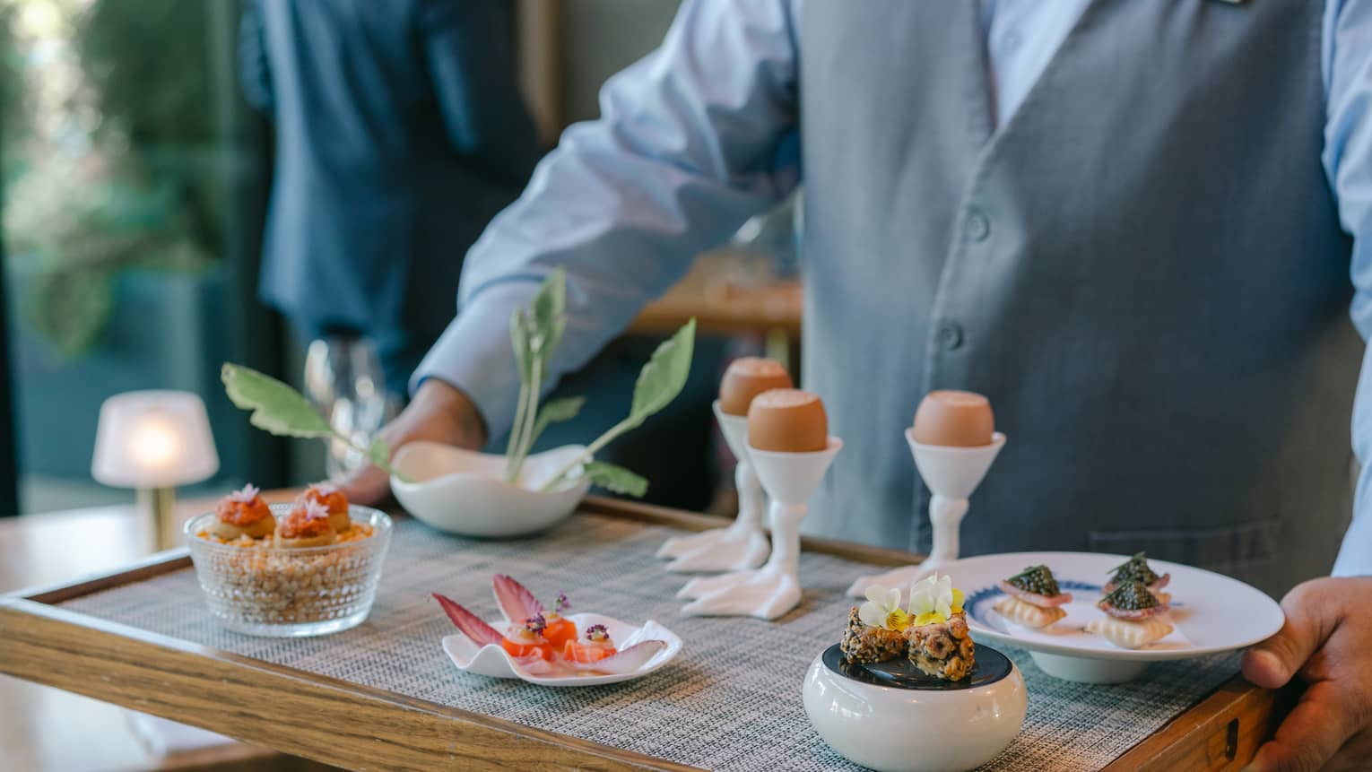 A person holding a tray of culinary dishes