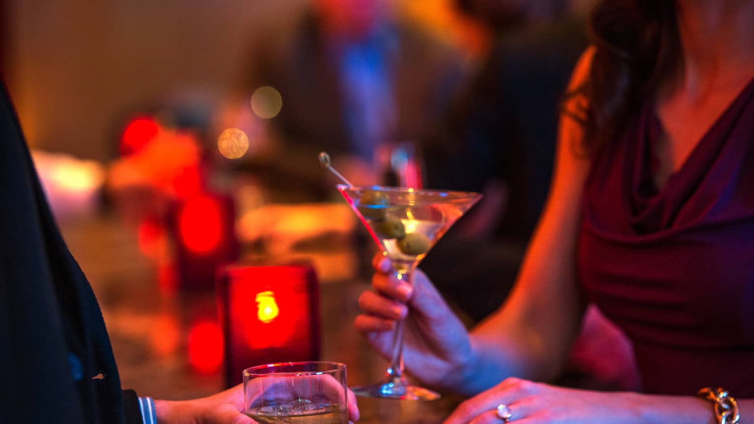 Ty Bar close-up of man and woman holding cocktails in rock and martini glasses, red candle